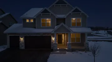 Tan two-storey with stone and dark garage doors